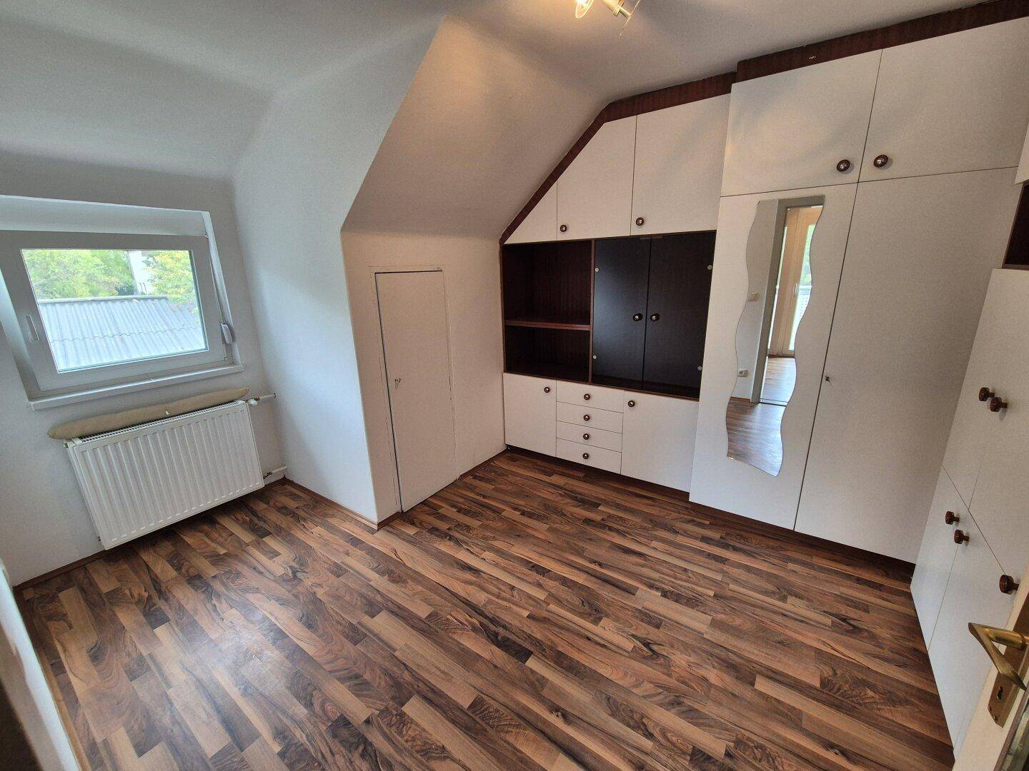 Schlafzimmer im Dachgeschoss mit Schrägen, Laminatboden und Einbauschränken.