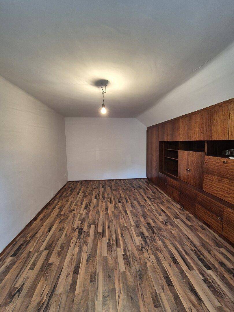 Geräumiger Raum mit Laminatboden und einer großen, integrierten Holzschrankwand.