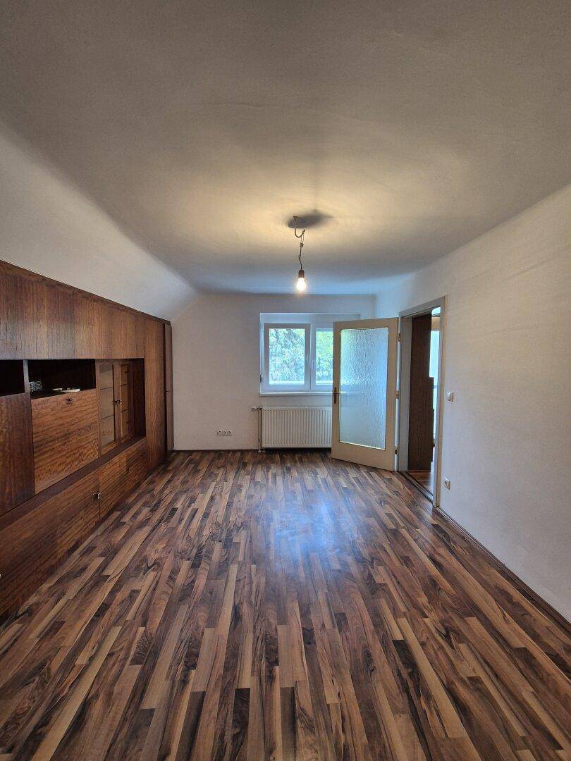 Helles Schlafzimmer mit Laminatboden, Holzschrankwand und Zugang zu einem weiteren Raum.