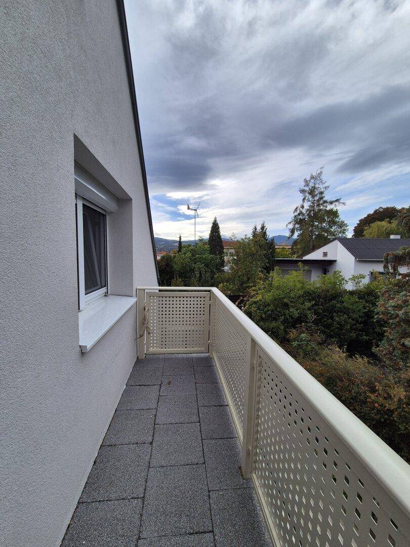 Kleiner Balkon mit Fliesenboden und Blick auf die grüne Umgebung.