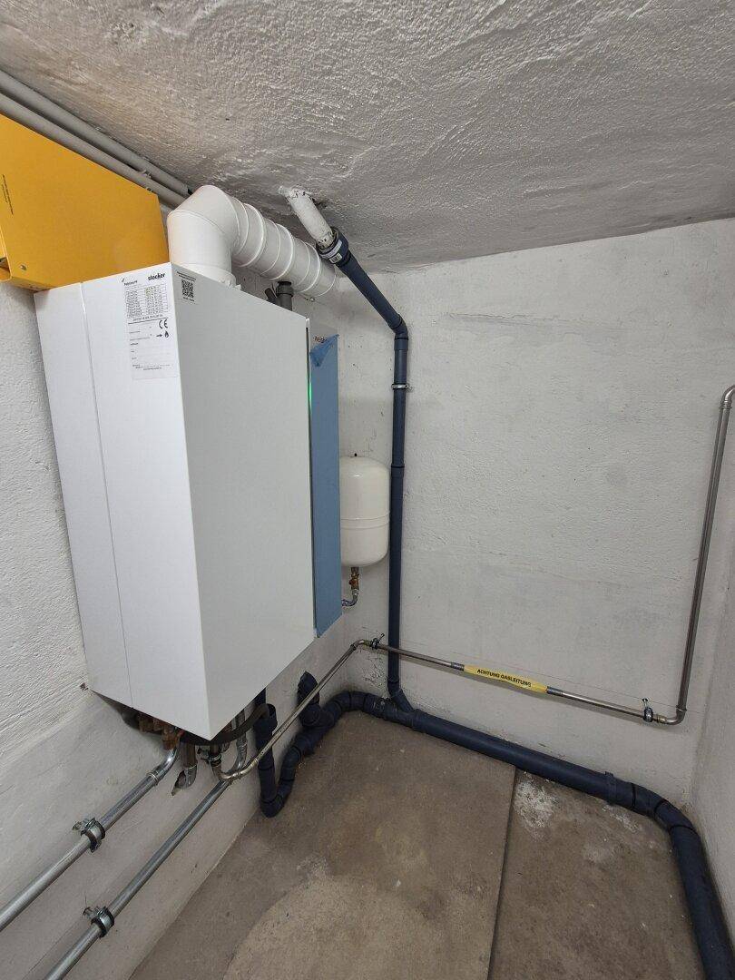 Heizungsanlage im Keller mit modernen Geräten und sichtbaren Installationen.