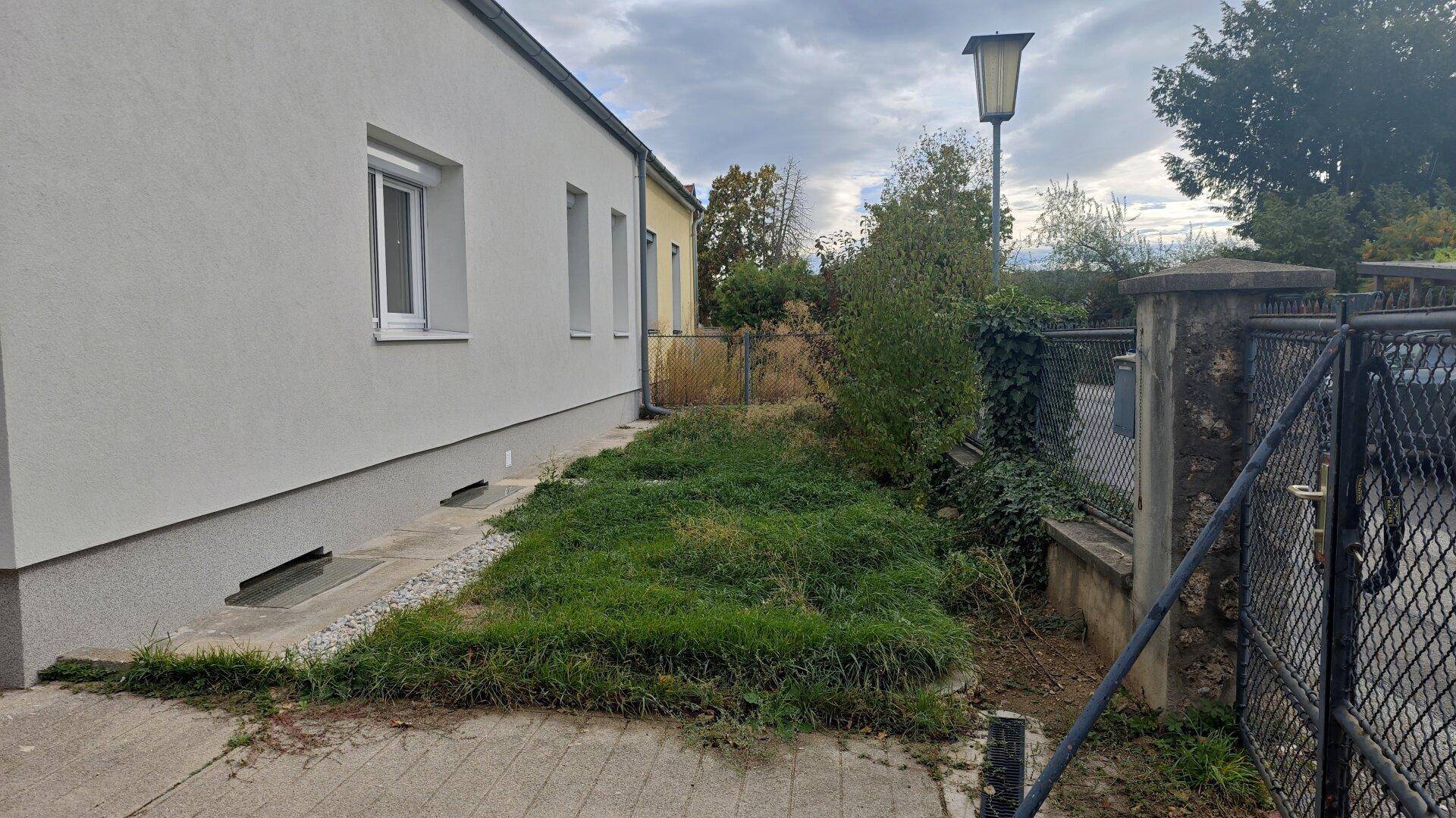 Seitenansicht des Hauses mit einem ungenutzten Gartenbereich und einem Zaun.