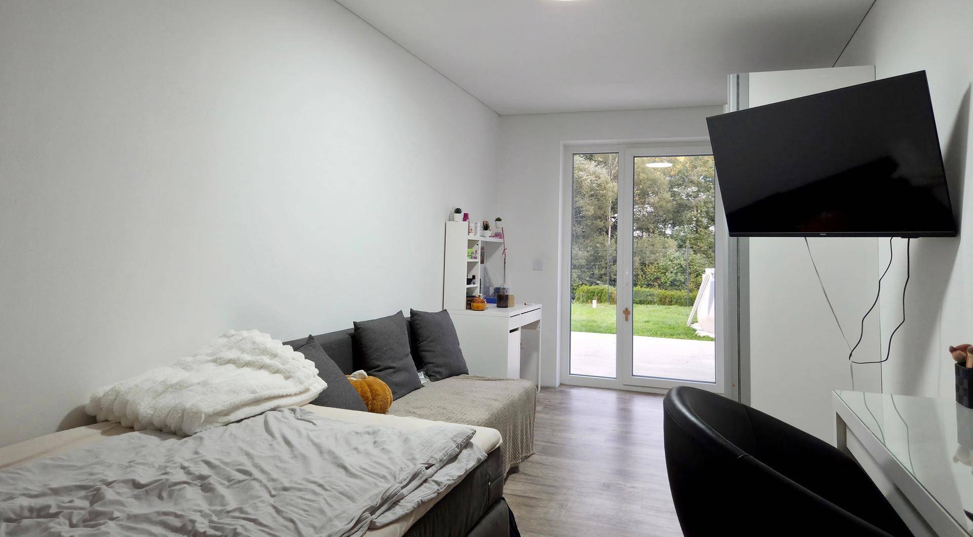 Helles Schlafzimmer mit Bett, Schreibtisch und direktem Zugang zum Gartenbereich.