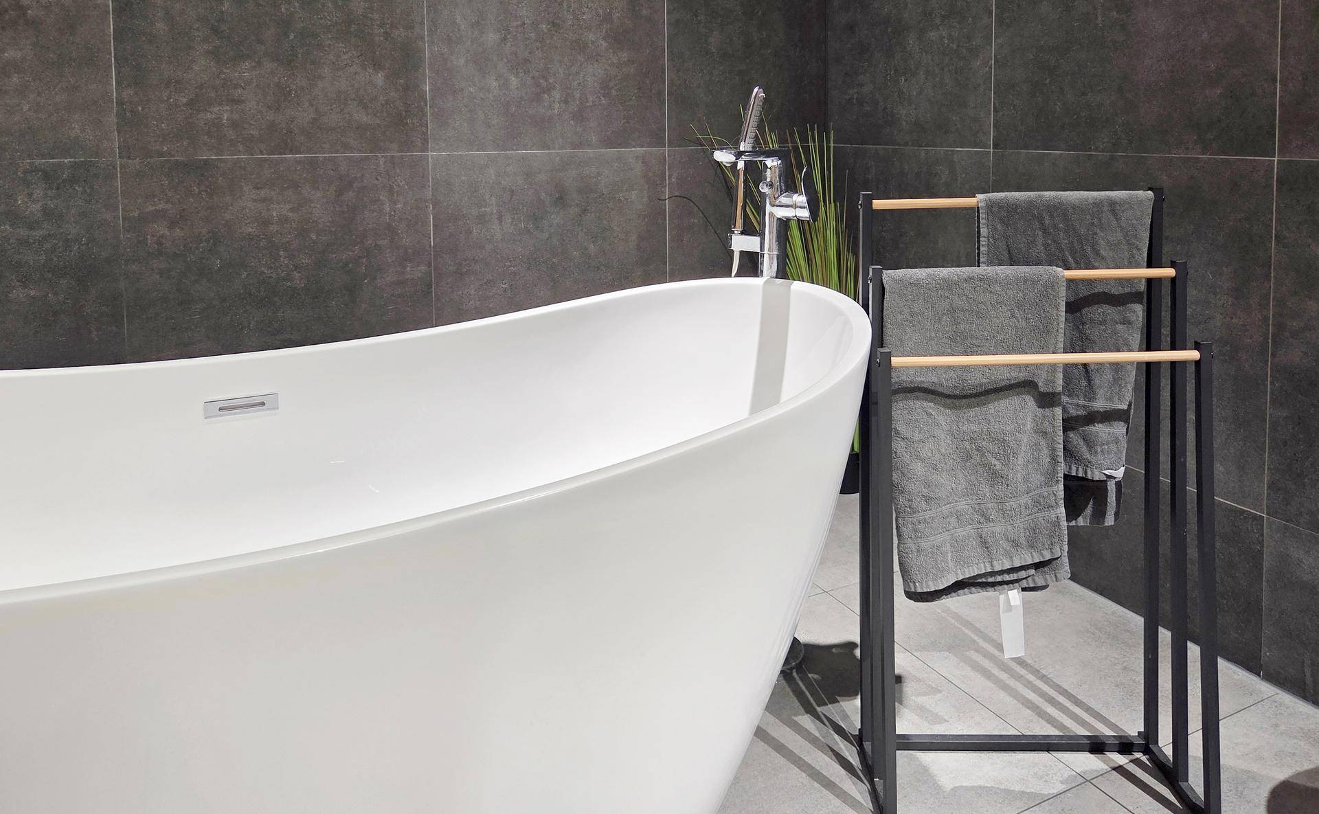 Detailansicht einer modernen freistehenden Badewanne mit Armatur und Handtuchhalter.