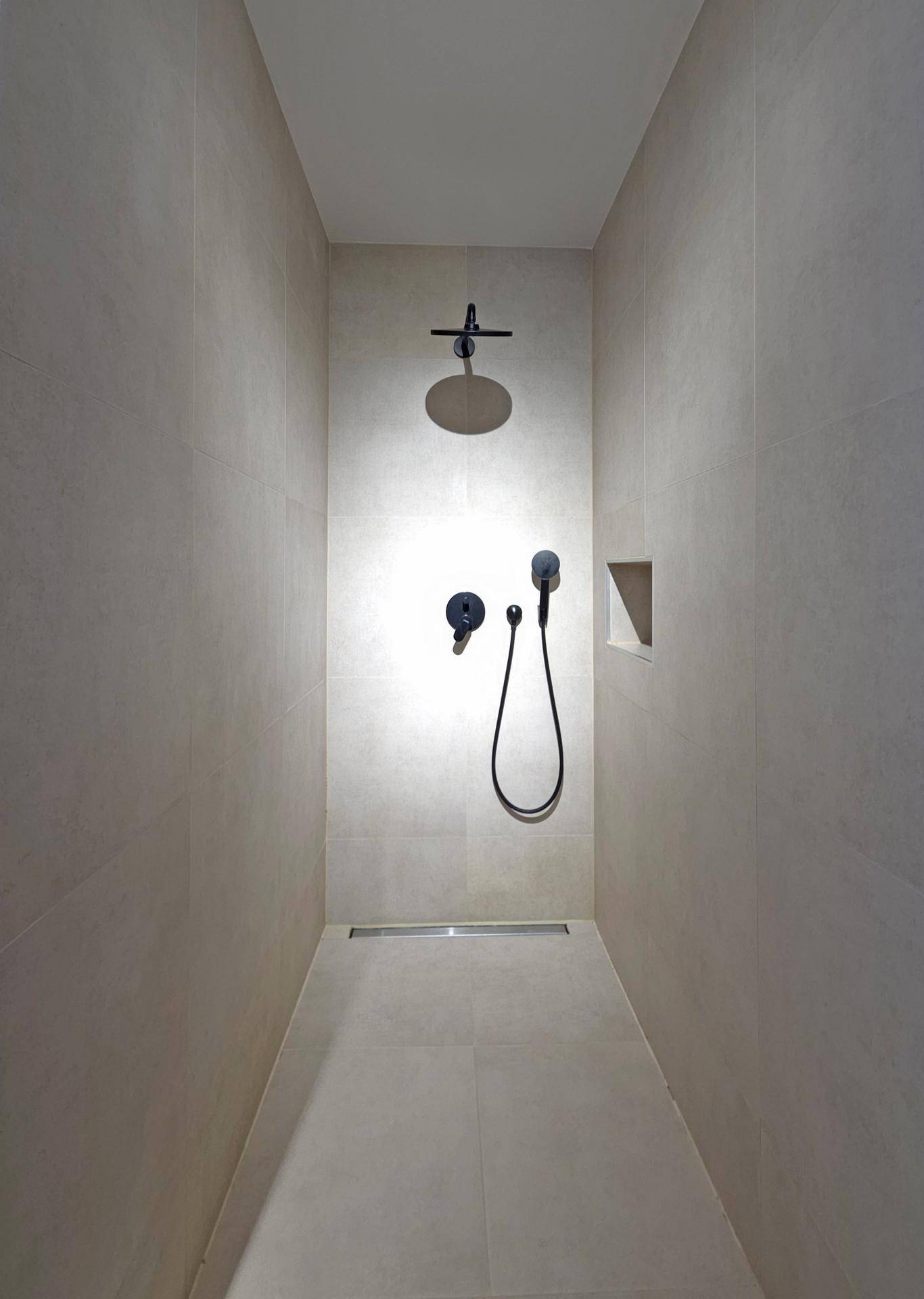 Moderne begehbare Dusche mit Regenduschkopf und minimalistischem Design in hellen Fliesen.