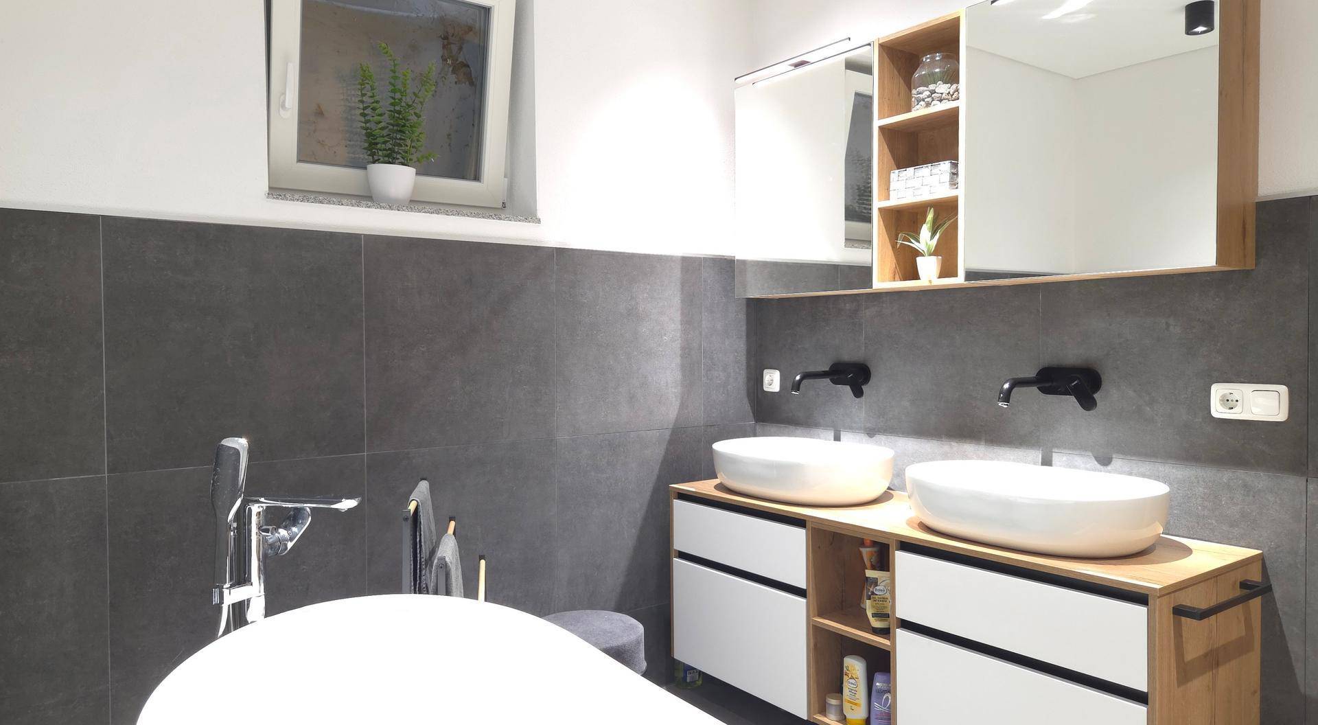 Geräumiges Badezimmer mit zwei Aufsatzwaschbecken, freistehender Badewanne und großem Spiegelschrank.