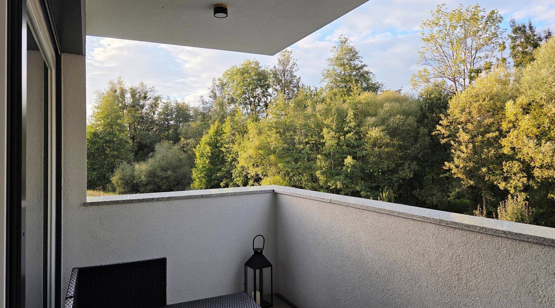 Heller Balkon mit Blick auf grüne Bäume, ideal für entspannte Stunden im Freien.