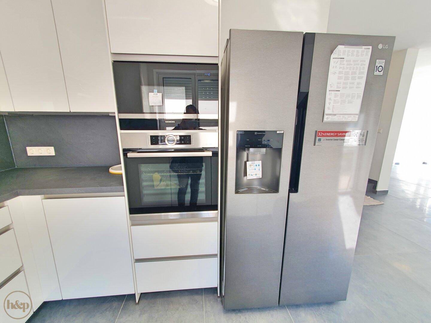 Hochwertige Einbaugeräte in der modernen Küche, inklusive Backofen und großem Kühlschrank.