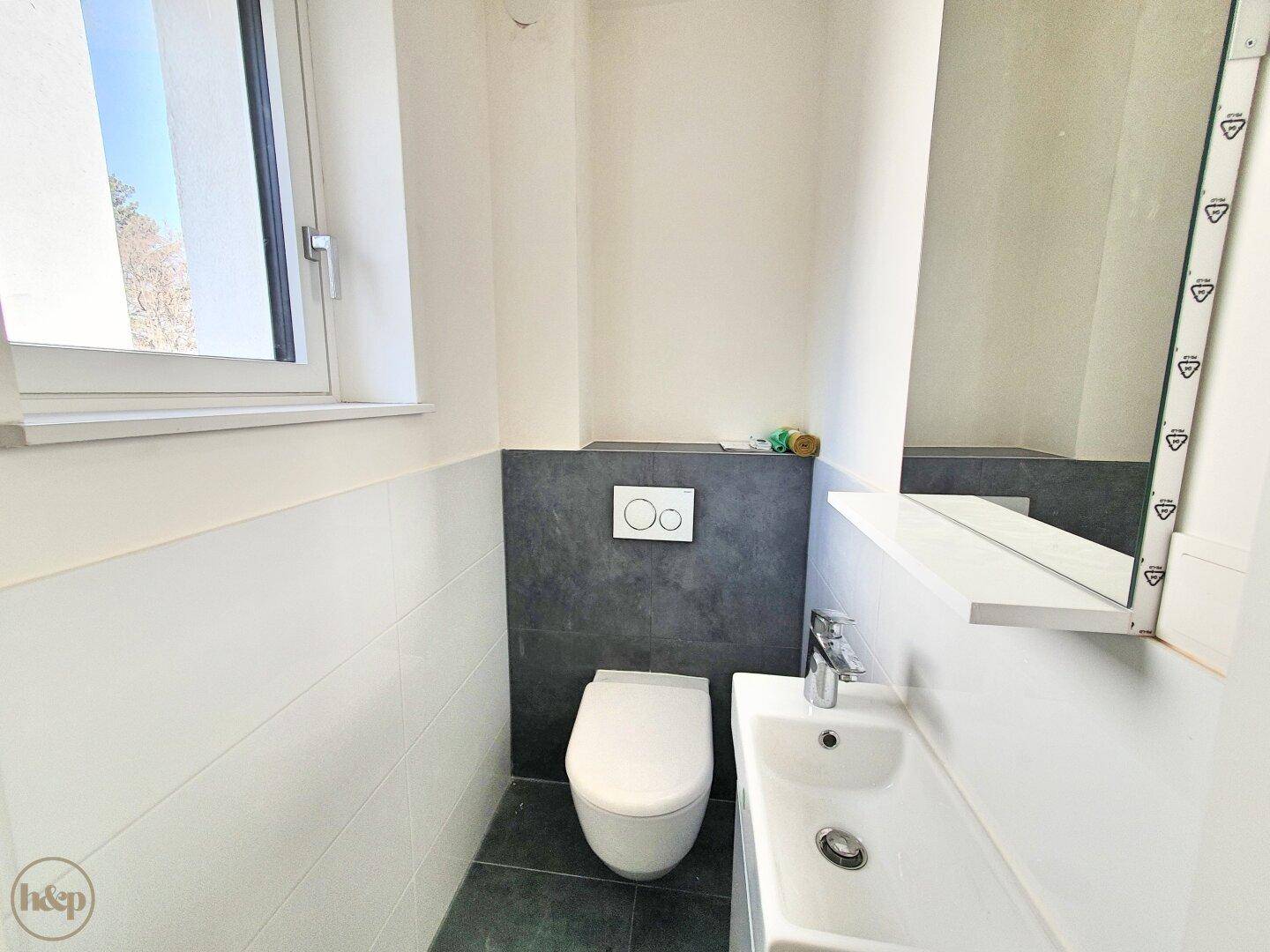 Modernes Gäste-WC mit wandhängendem WC, kleinem Waschbecken und Fenster.