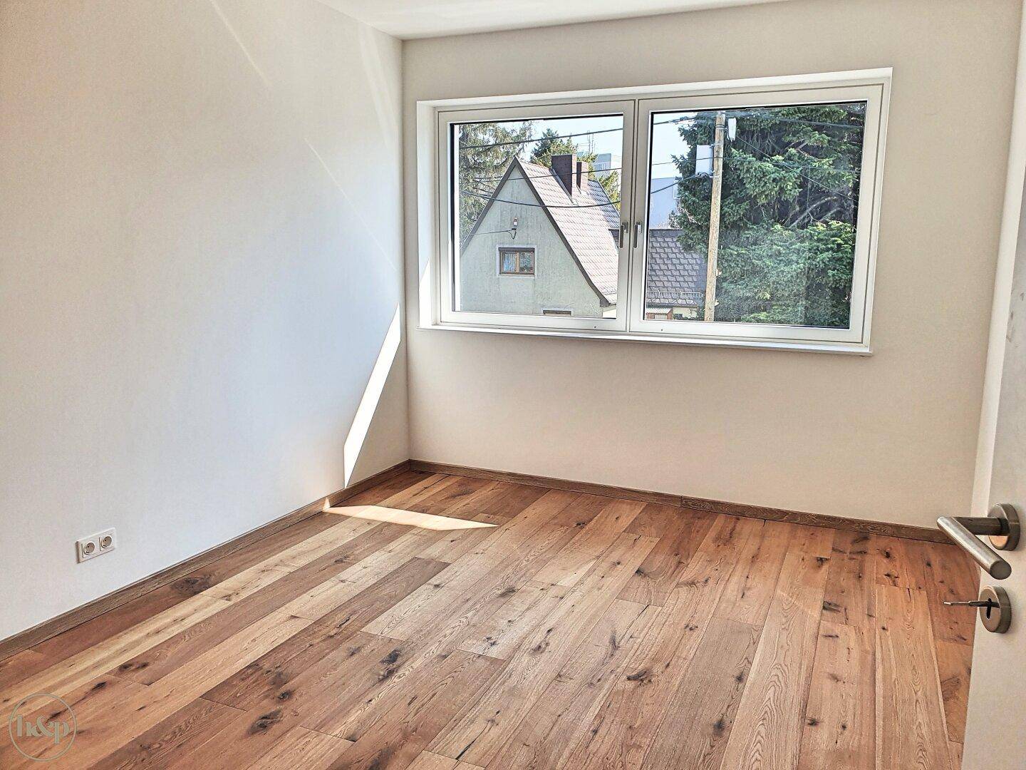 Gemütliches Schlafzimmer mit Holzboden und Fenster, das viel Tageslicht hereinlässt.