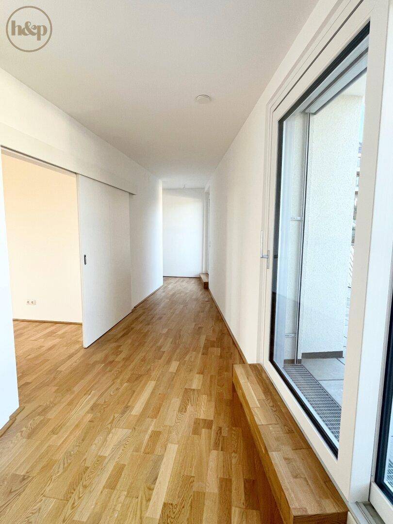 Langer, heller Flur mit Holzboden und Schiebetüren, führt zu weiteren Räumen.