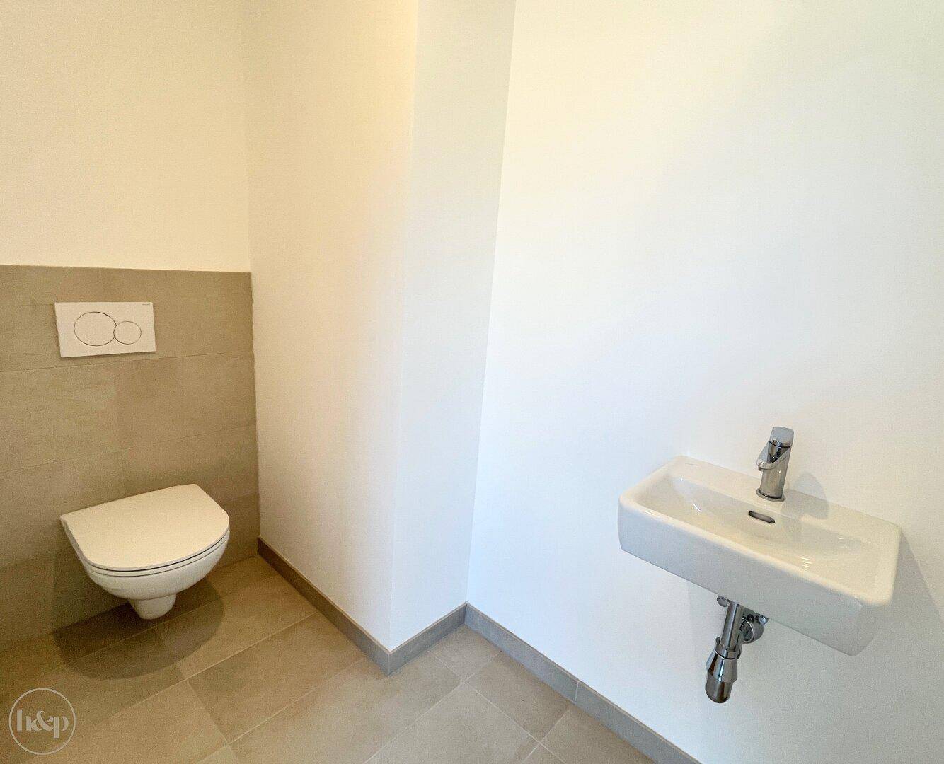 Kleines Gäste-WC mit modernen grauen Fliesen und wandhängender Toilette.
