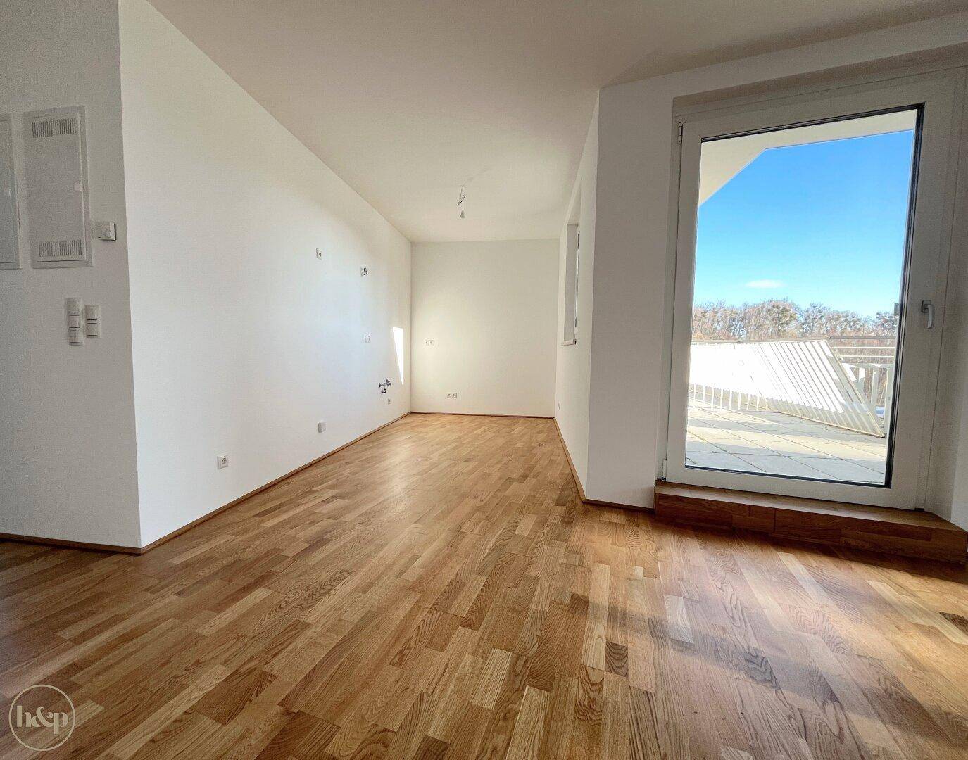 Geräumiges, helles Zimmer mit Holzboden und Zugang zu einem Außenbereich.