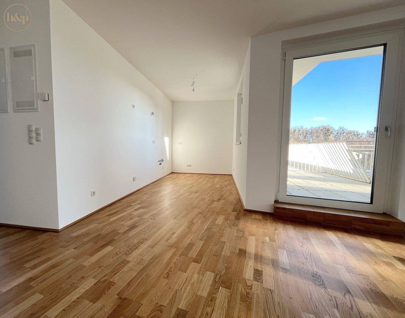 Geräumiger, heller Raum mit Parkettboden und Zugang zu einem Außenbereich.