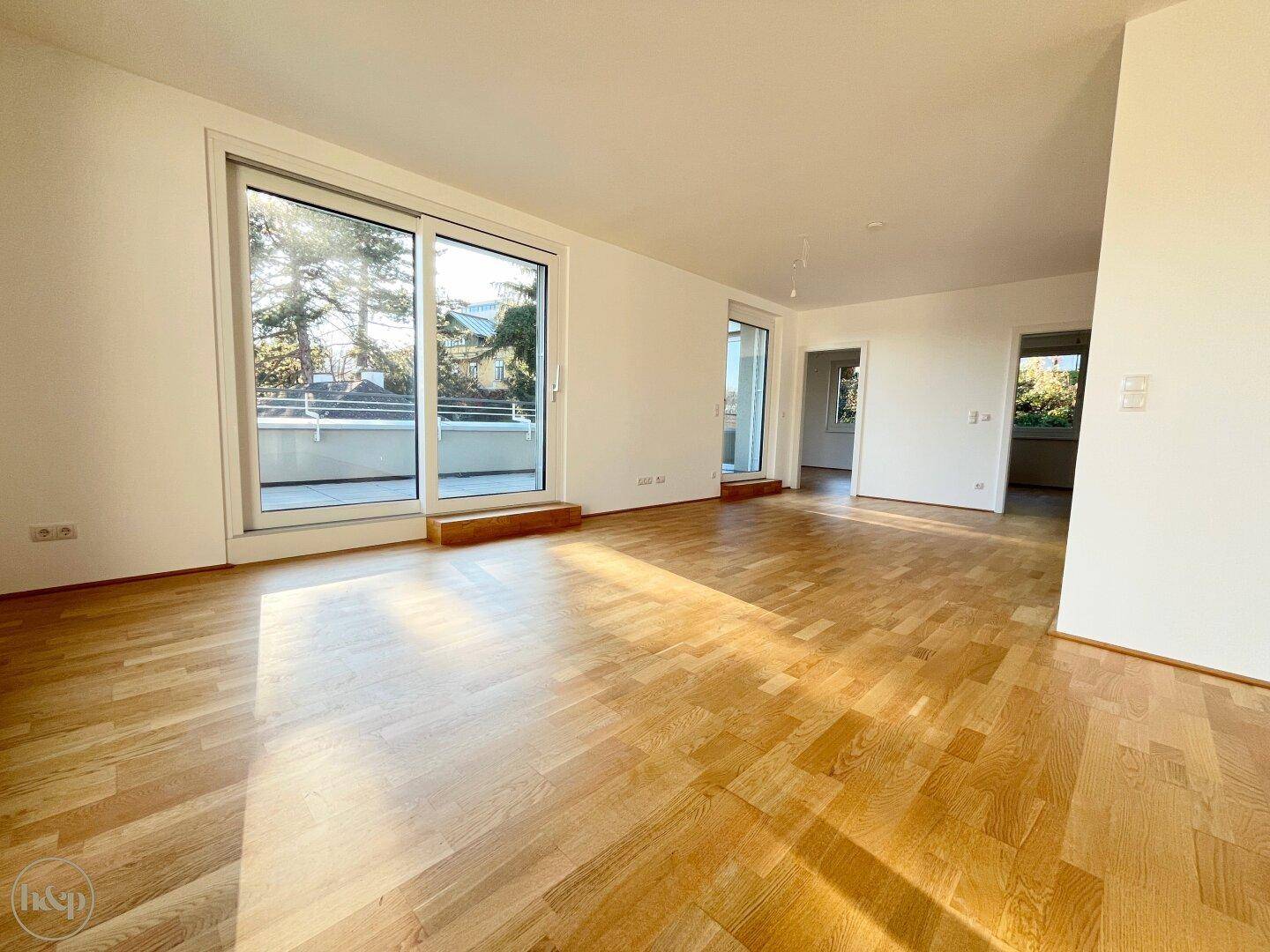 Großes, helles Wohnzimmer mit Holzboden und Schiebetüren zu einem Balkon.