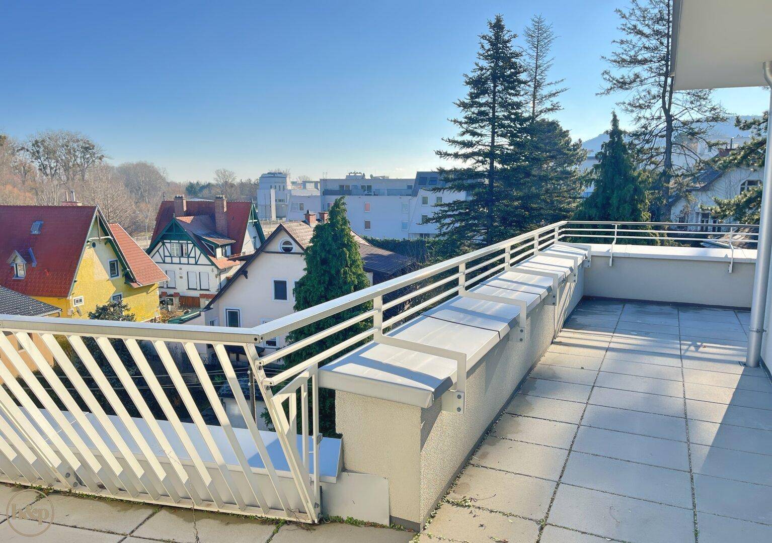 Geräumige Terrasse mit Fliesenboden und weißem Geländer, bietet einen weiten Ausblick.