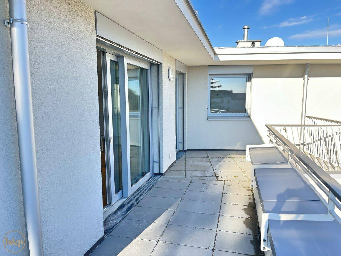 Heller Balkon mit Fliesenboden und Schiebetüren, bietet Zugang zum Innenbereich.