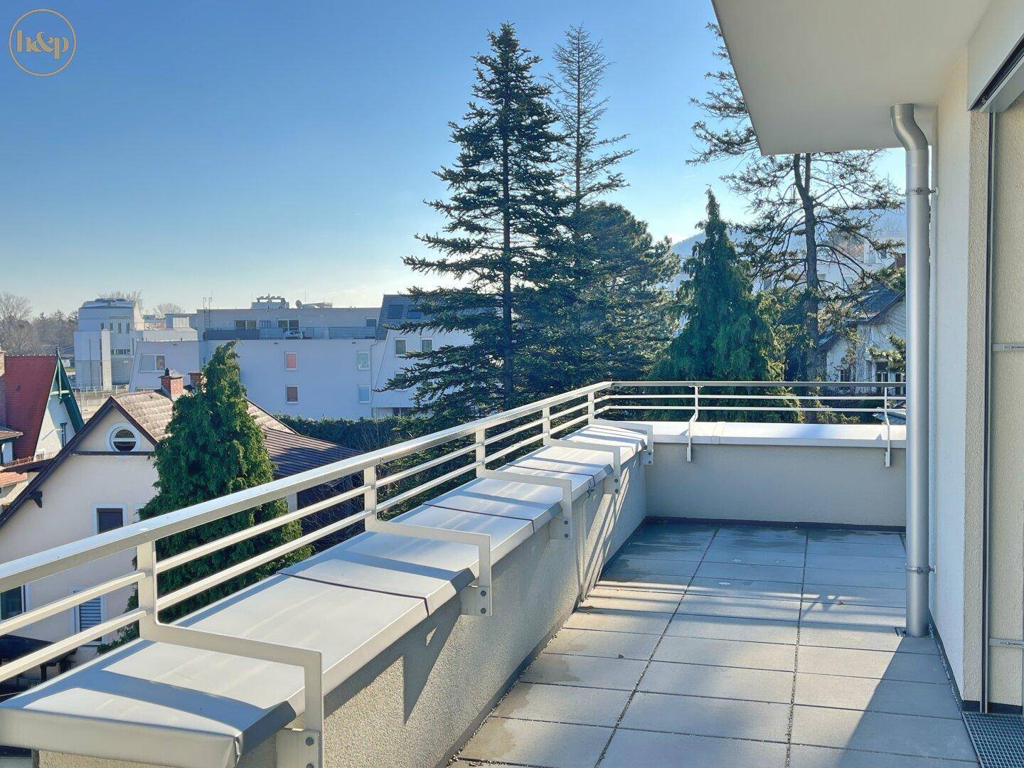 Geräumige Terrasse mit Fliesenboden und weitem Blick auf die grüne Umgebung.