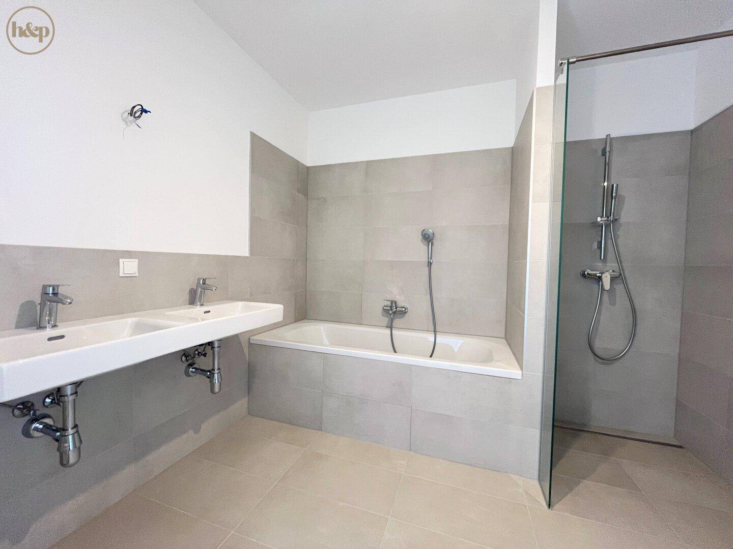 Geräumiges Badezimmer mit Badewanne, Doppelwaschbecken und moderner Dusche.