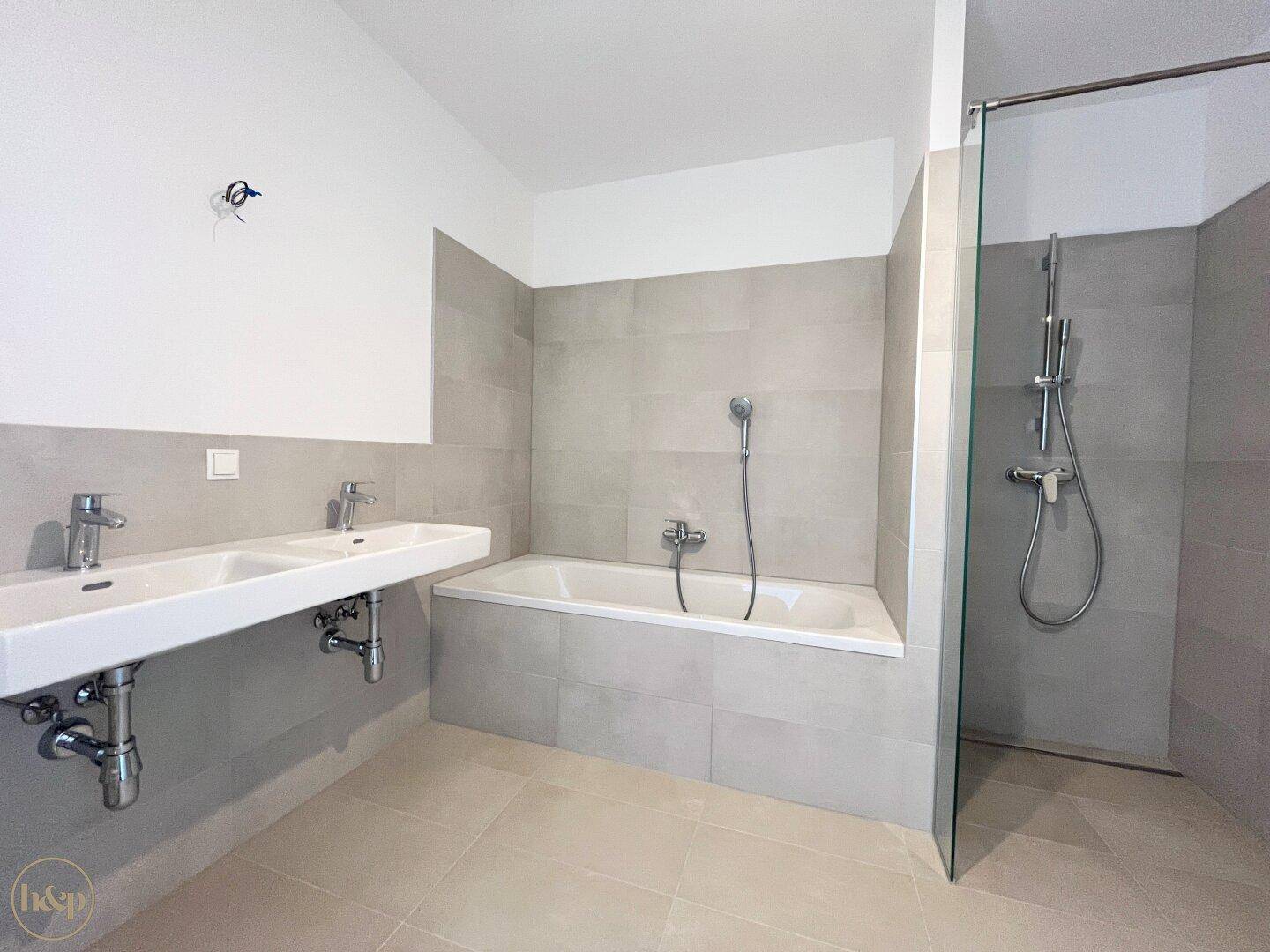 Geräumiges Badezimmer mit Doppelwaschbecken, Badewanne und begehbarer Dusche.