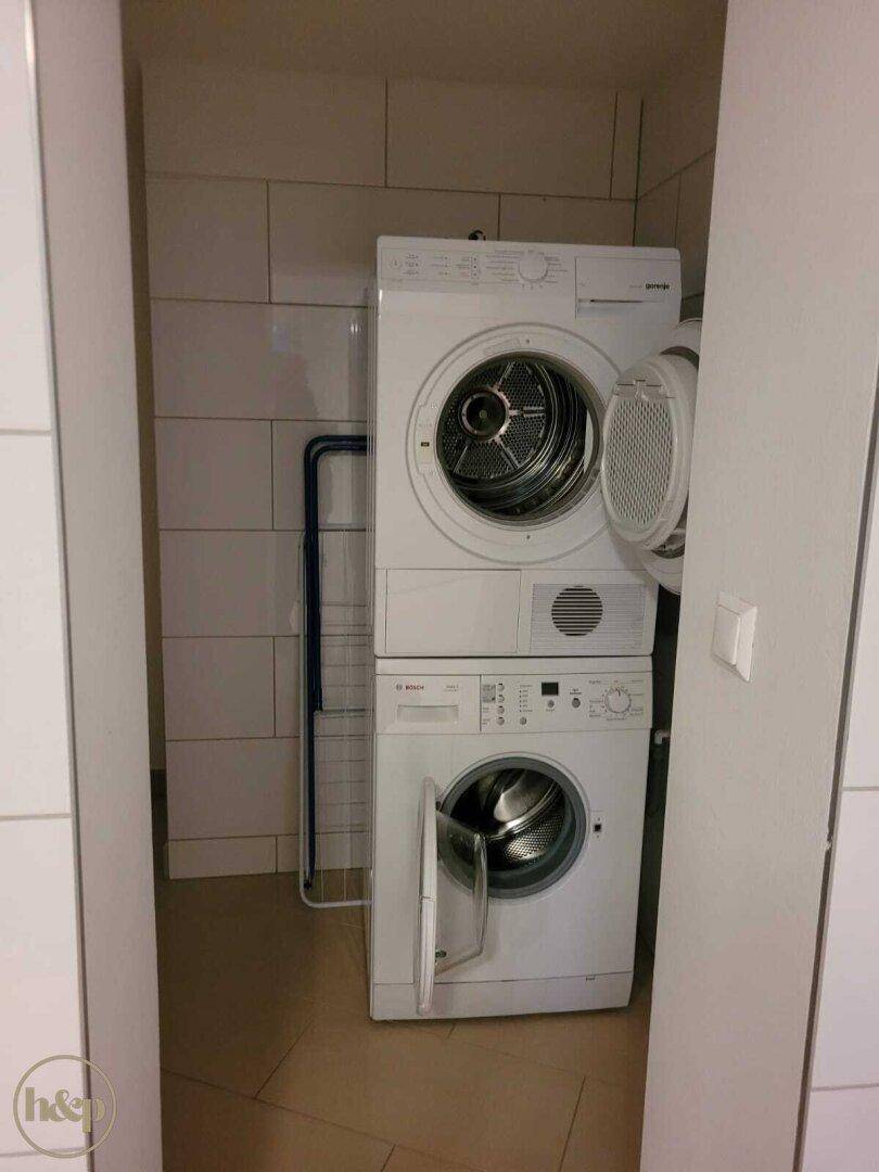 Kleiner Hauswirtschaftsraum mit gestapelter Waschmaschine und Trockner.