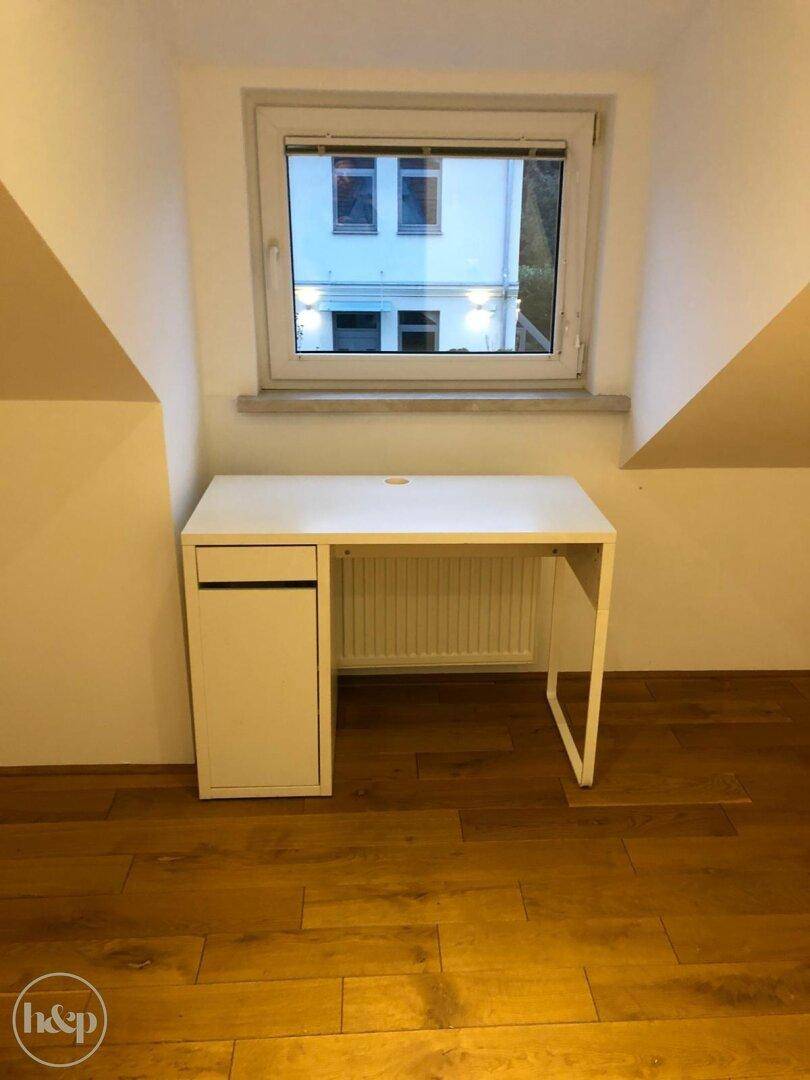 Arbeitszimmer im Dachgeschoss mit Schreibtisch, Fenster und Holzboden.