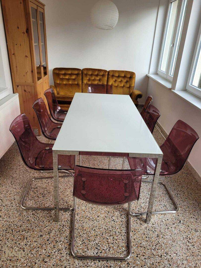 Esszimmer mit modernem Esstisch, transparenten Stühlen und Terrazzoboden.