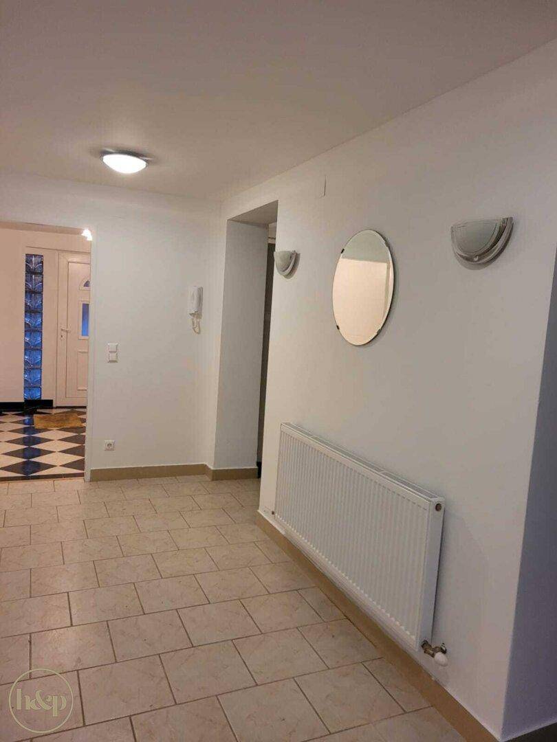 Heller Flur mit Fliesenboden, Heizkörper und Spiegel an der Wand.