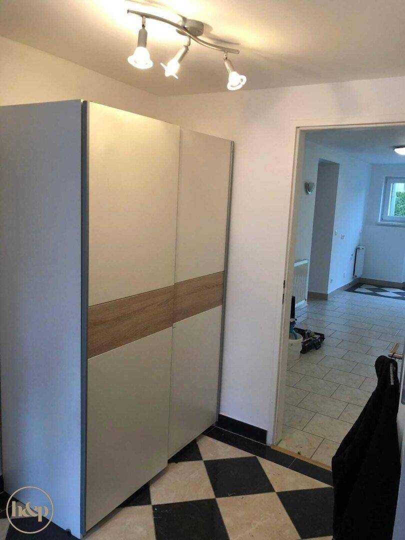 Eingangsbereich mit modernem Kleiderschrank, Fliesenboden und Zugang zu weiteren Räumen.
