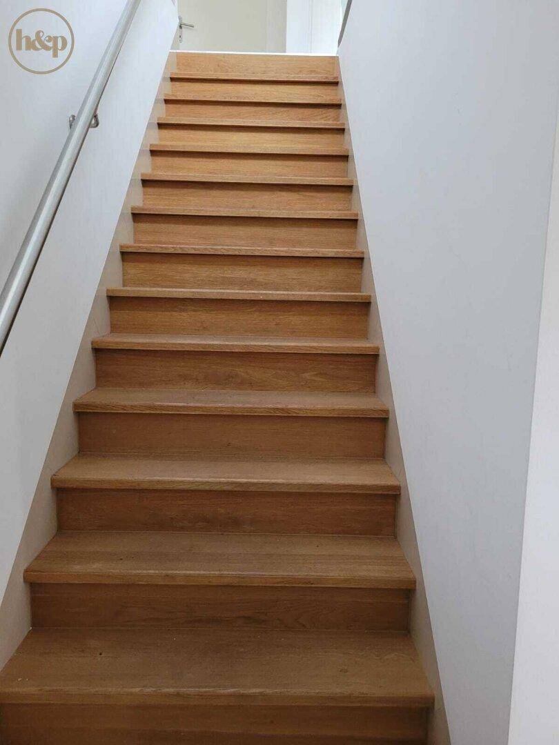 Elegante Holztreppe mit Metallgeländer, verbindet die verschiedenen Etagen des Hauses.