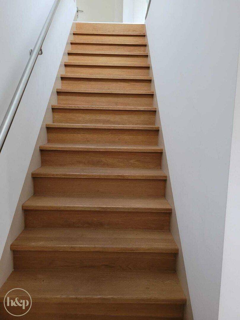 Holztreppe mit Metallgeländer, die in die oberen Stockwerke führt.