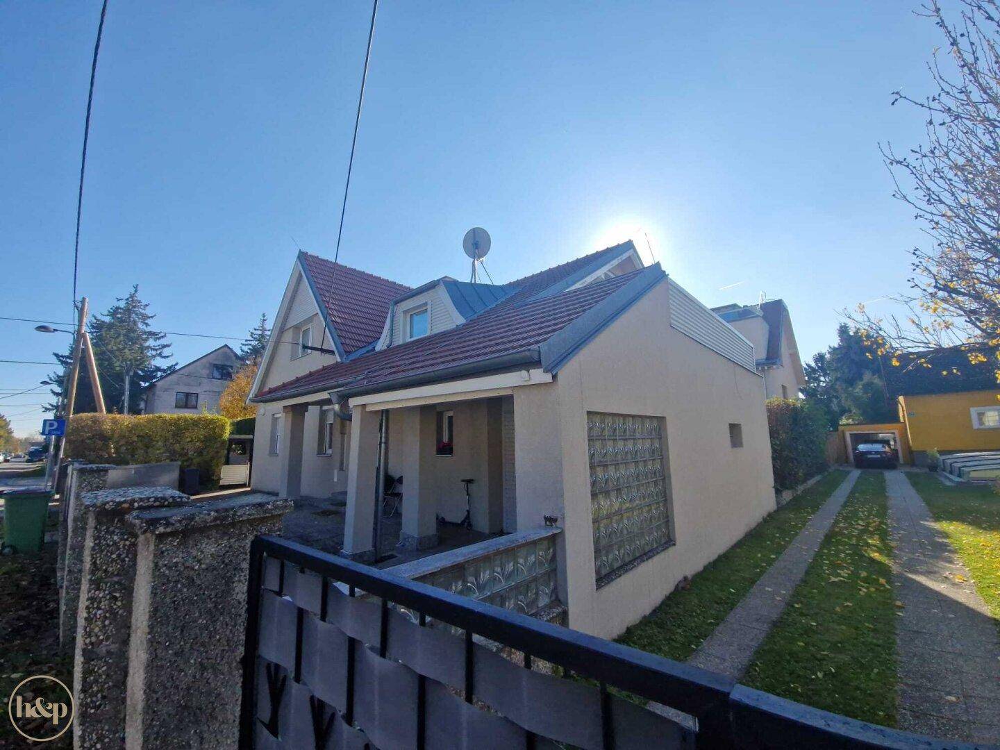 Einfamilienhaus mit Satteldach, Vorgarten und Einfahrt an einem sonnigen Herbsttag.