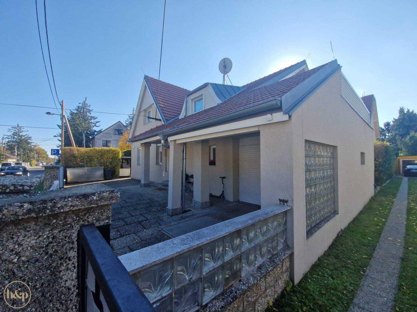 Seitenansicht des Hauses mit gepflasterter Einfahrt, Glasbausteinen und Blick auf die Straße.
