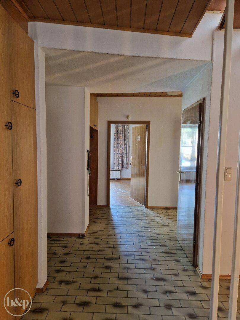 Flur mit Fliesenboden und Holzdecke, der zu weiteren Zimmern führt.