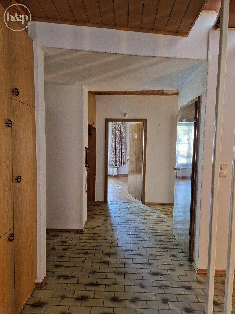 Langer Flur mit Fliesenboden, der zu verschiedenen Zimmern führt.