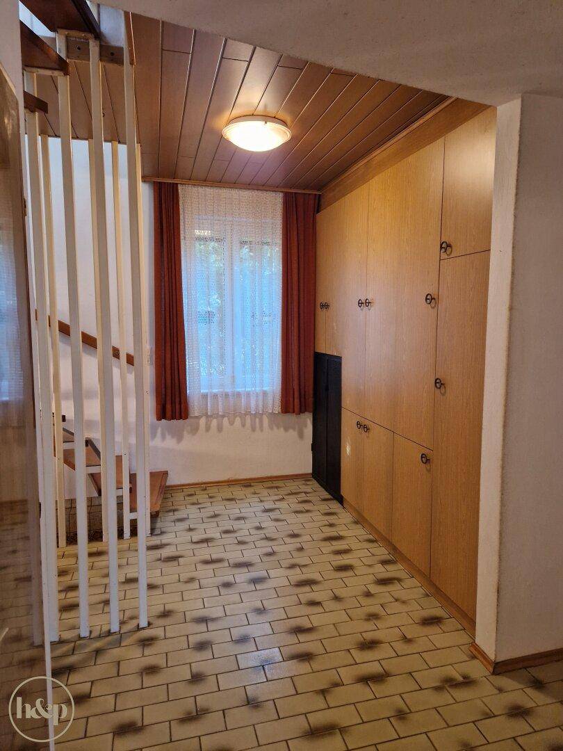 Geräumiger Flur mit Einbauschränken, Holzdecke und Treppenaufgang.