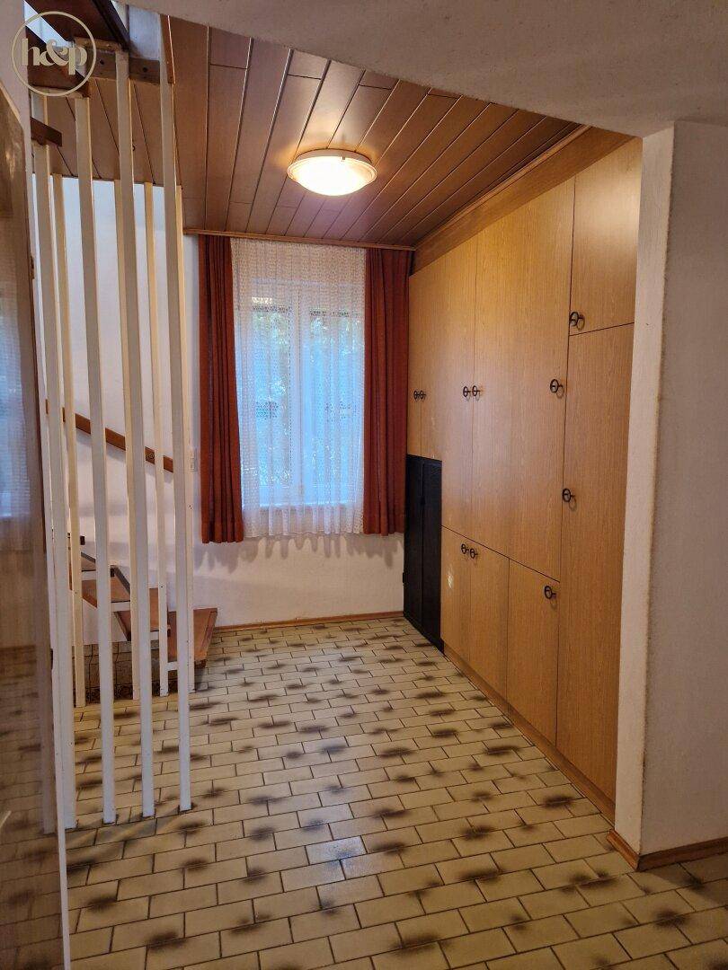 Geräumiger Flur mit Einbauschränken aus Holz und Treppenaufgang.