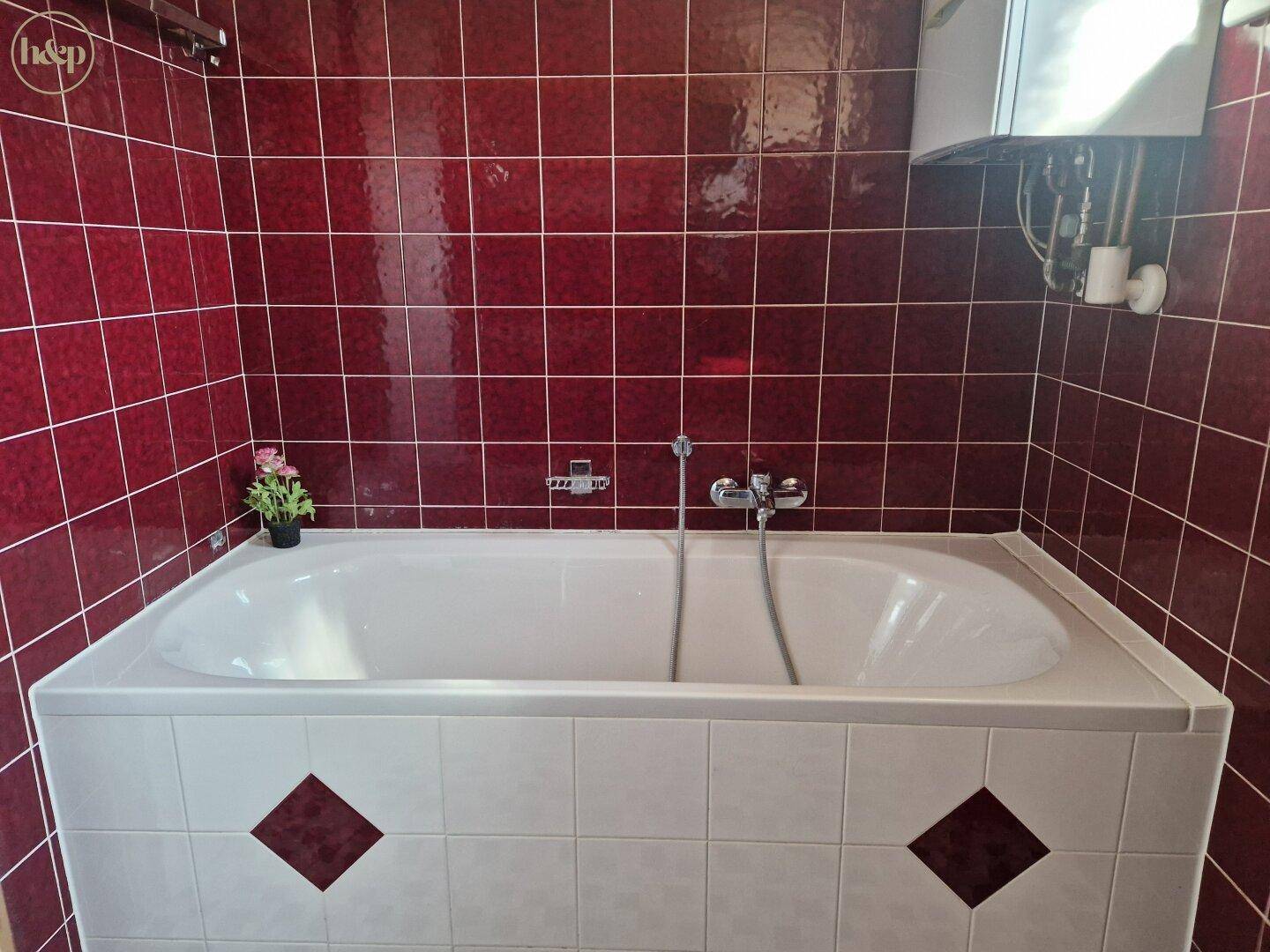 Badezimmer mit roten Fliesen und einer eingebauten Badewanne.