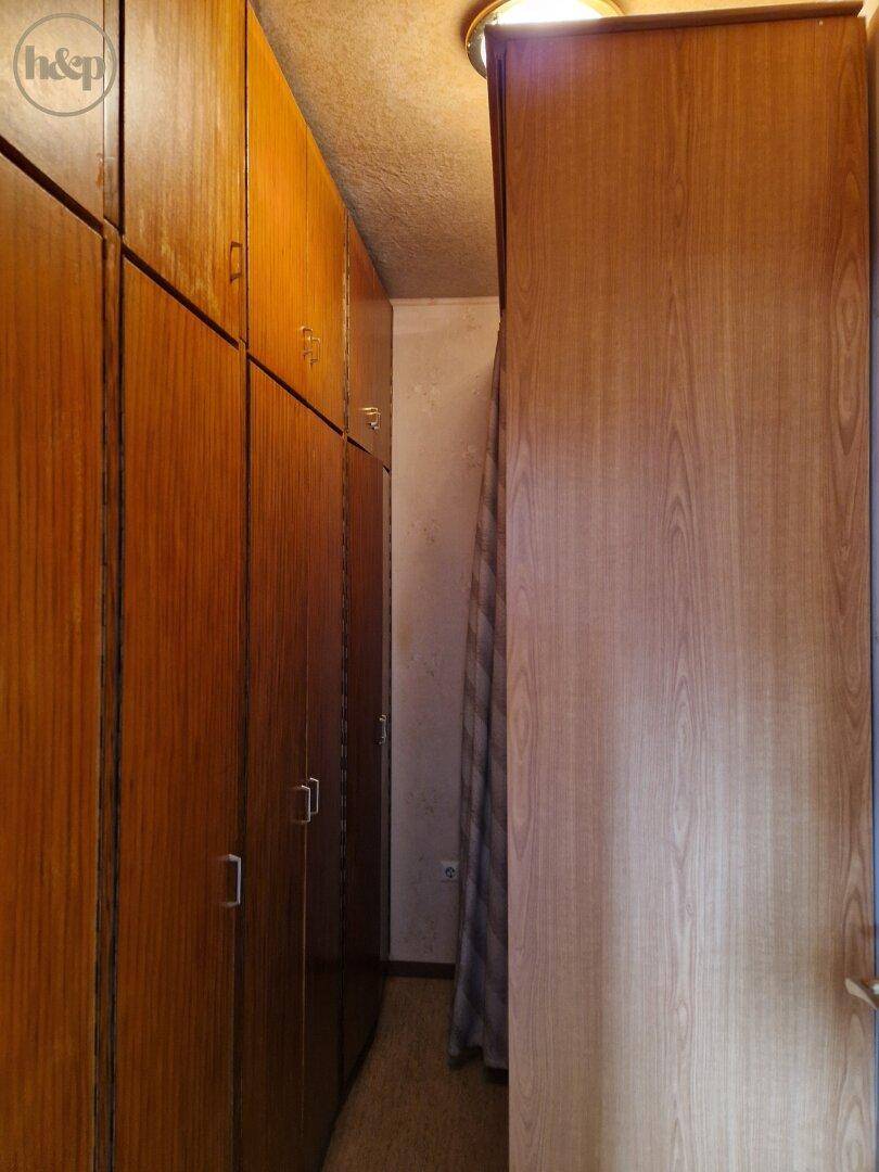 Praktischer begehbarer Kleiderschrank mit vielen Holzschränken für Stauraum.