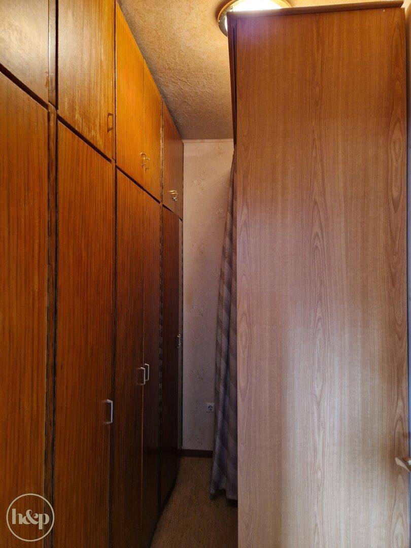 Langer begehbarer Kleiderschrank mit vielen Holzschränken.
