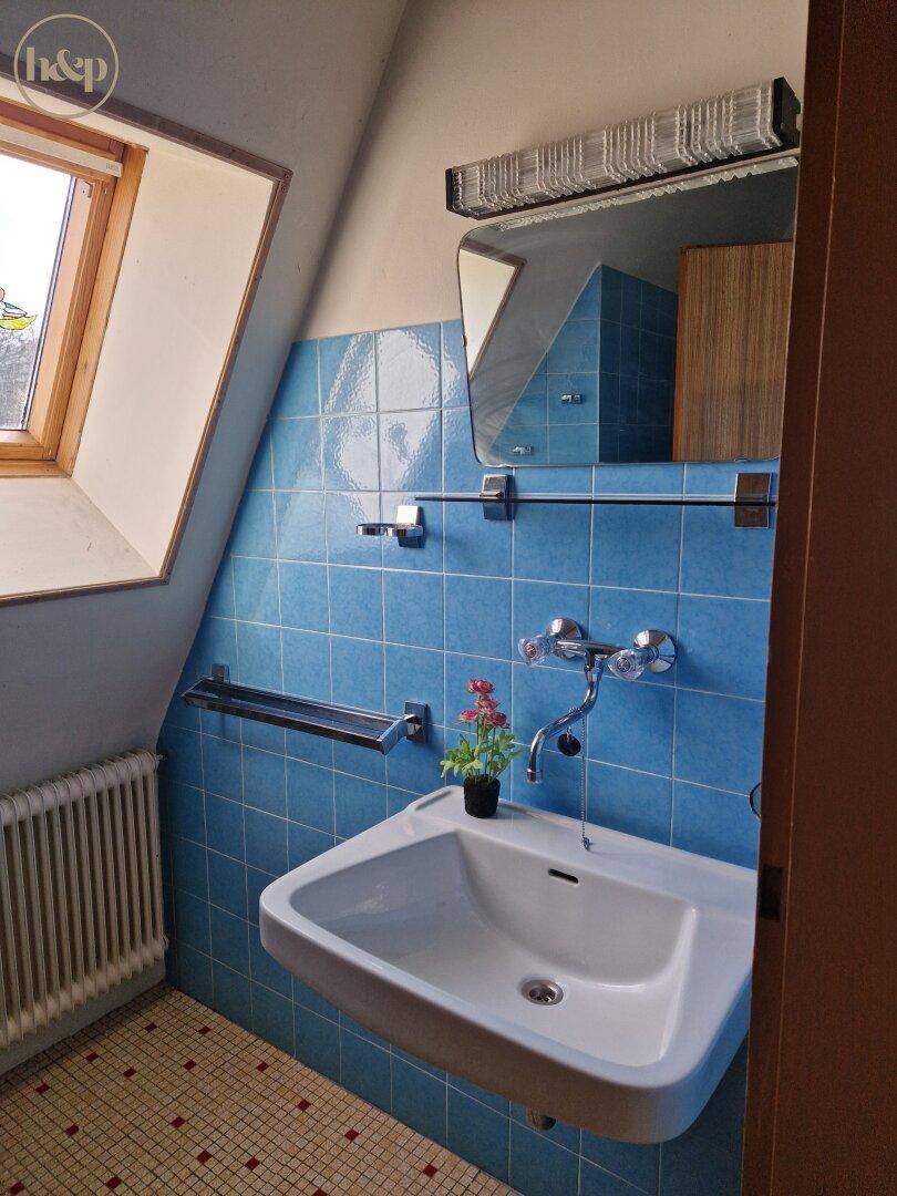 Badezimmer mit blauen Fliesen, Einzelwaschbecken und Dachfenster.