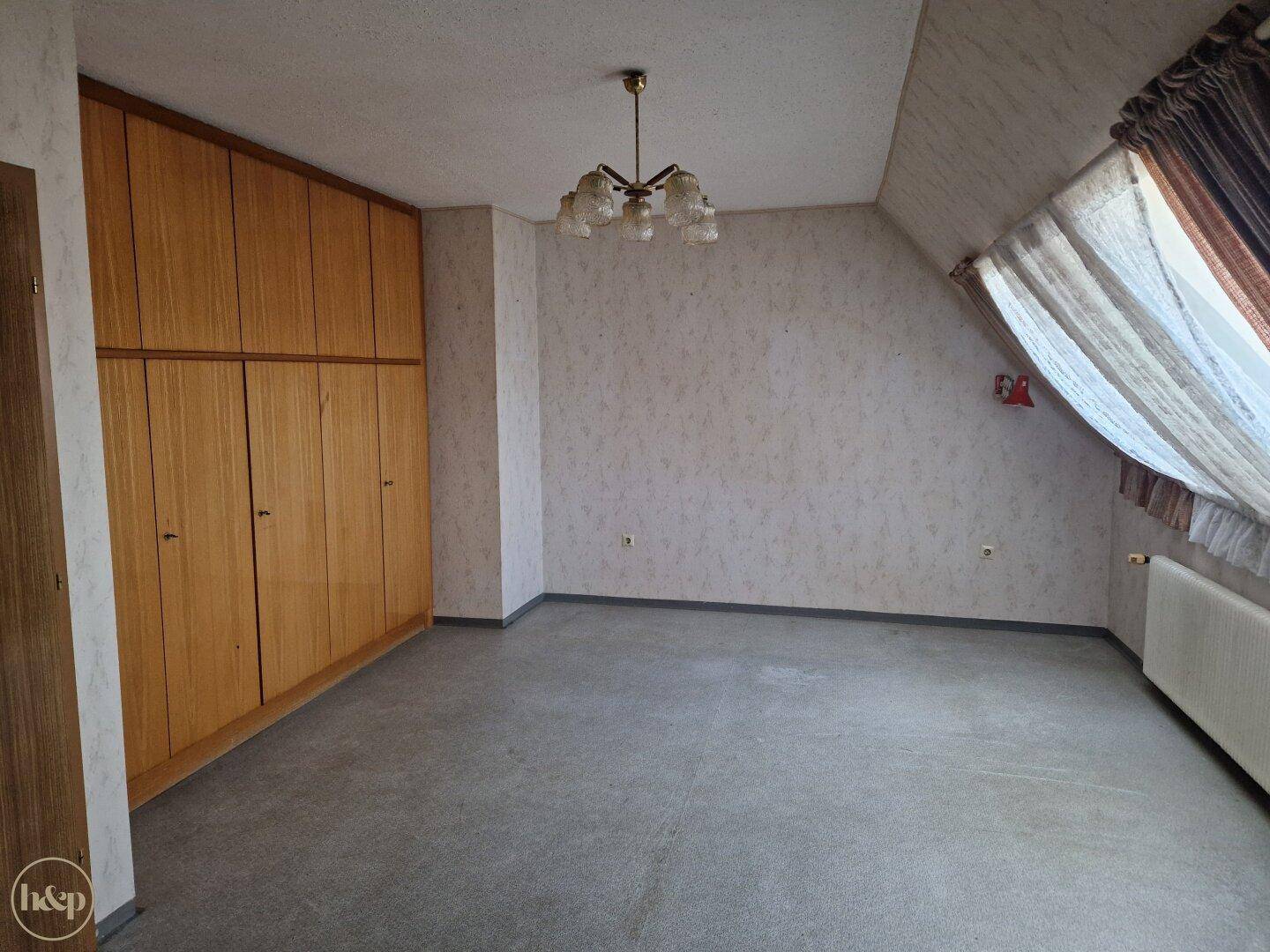 Geräumiges Schlafzimmer mit Teppichboden, Einbauschränken und Dachschräge.