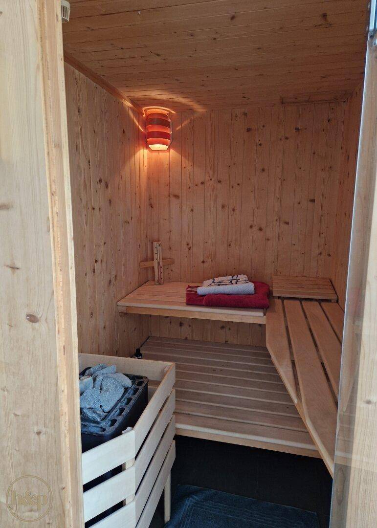 Gemütliche Holzsauna mit Bänken und indirekter Beleuchtung für Entspannung.