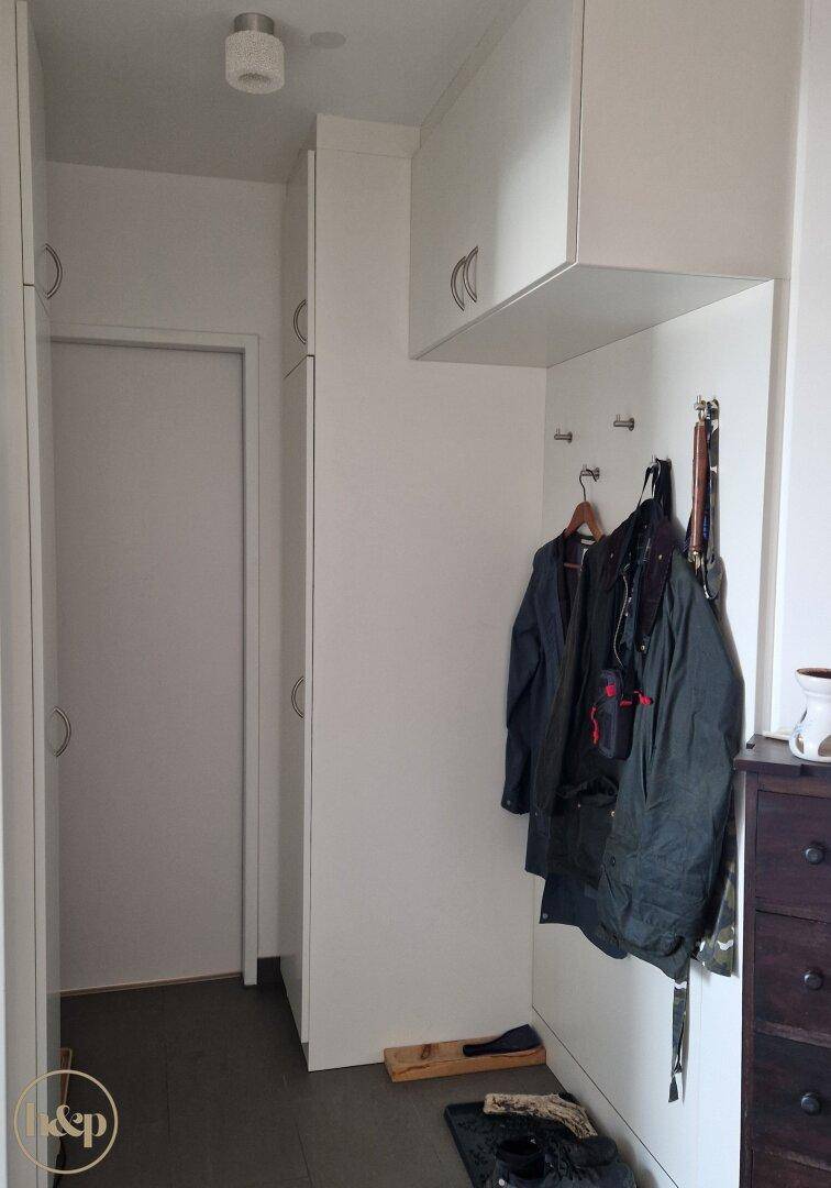 Heller Flur mit Einbauschränken und Garderobe für Kleidung und Accessoires.