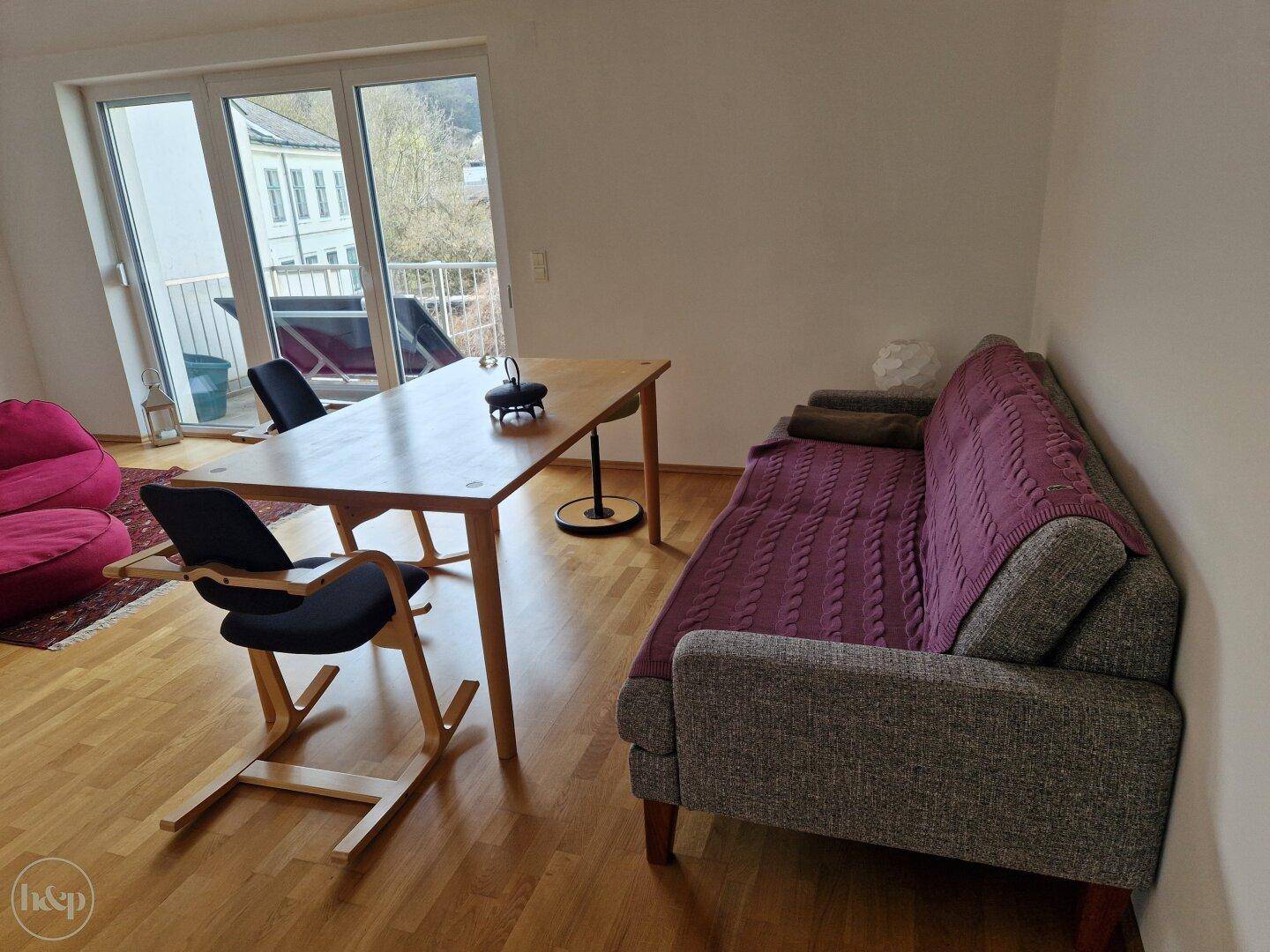 Wohn-Essbereich mit Sofa, Esstisch und Zugang zu einem Balkon.