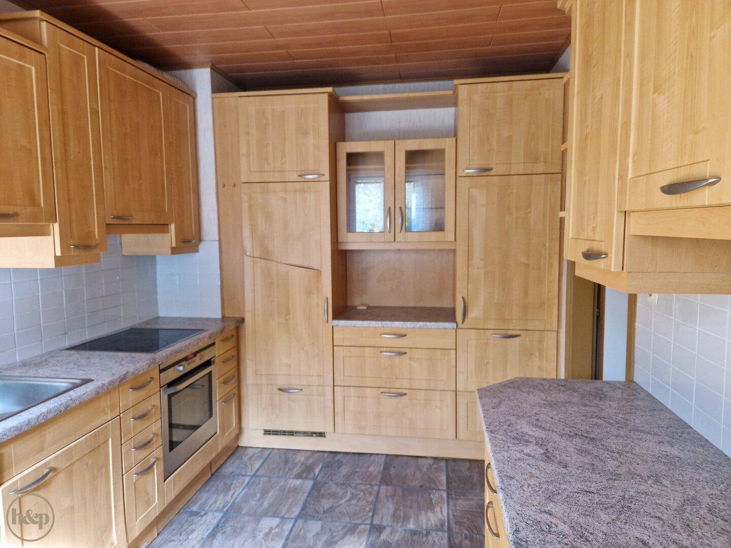 Voll ausgestattete Holzküche mit vielen Schränken und Arbeitsflächen.