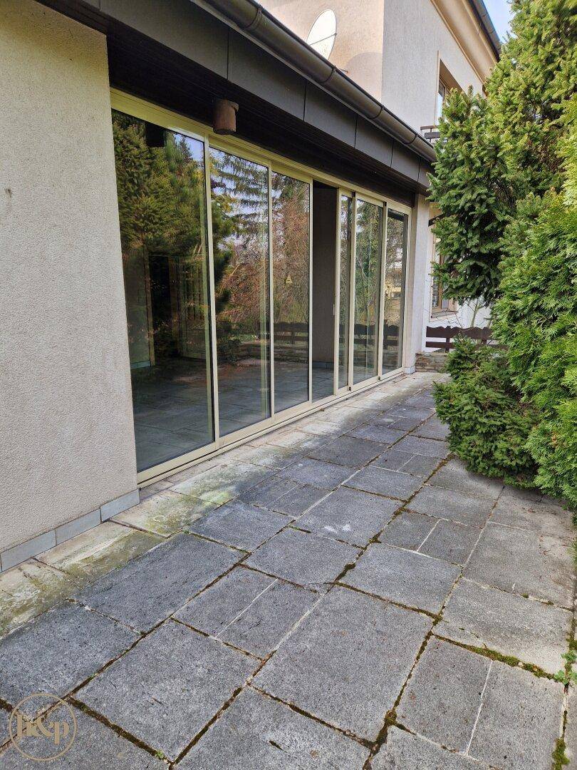 Gepflasterte Terrasse mit großen Glasschiebetüren, die den Zugang zum Innenbereich ermöglichen.