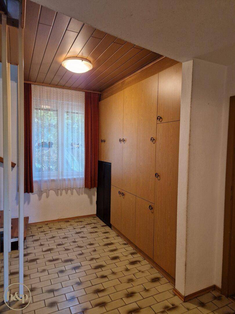 Heller Flur mit Einbauschränken, Fenster und Holzdecke, Treppenaufgang sichtbar.