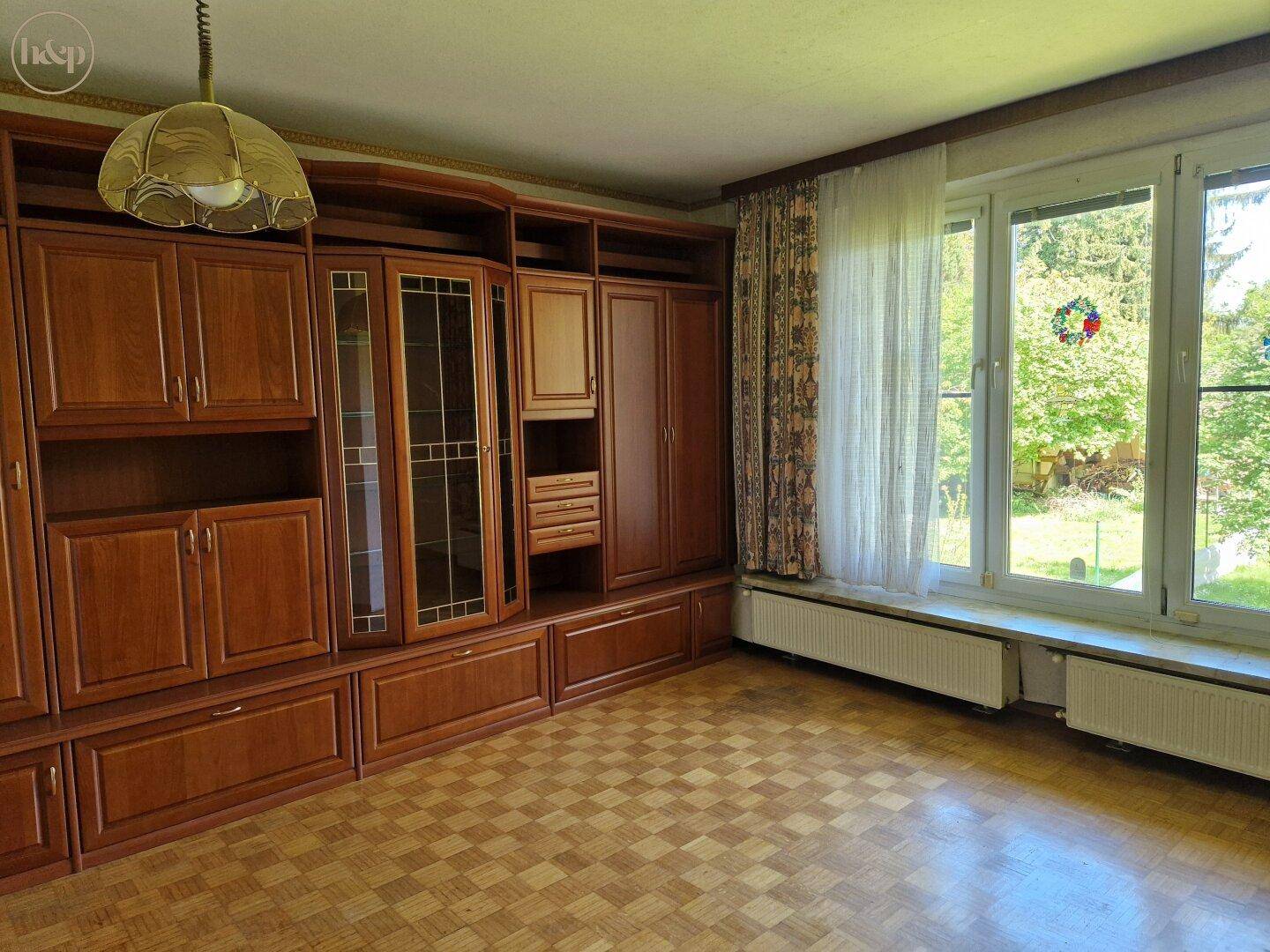 Gemütliches Wohnzimmer mit großer Holzschrankwand und Parkettboden.