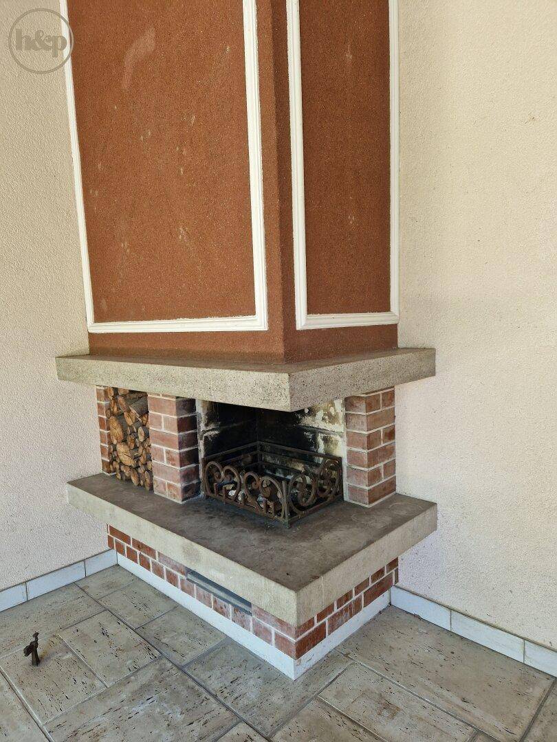 Detailansicht des gemauerten Kamins mit Holzablage im Wintergarten.